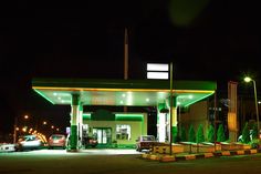 an empty gas station at night with cars parked