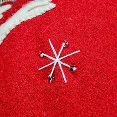 a snowflake is laying on top of a red carpet with pins sticking out of it