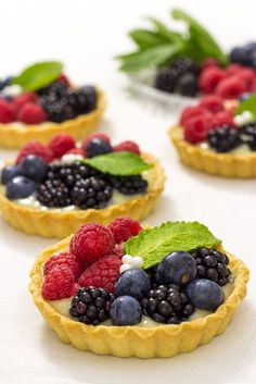 small tarts filled with berries and mint leaves