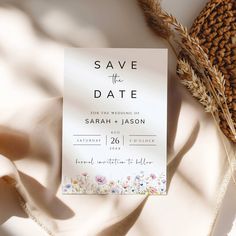 save the date card on top of a blanket with dried wheat and flowers in it