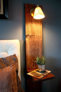 a lamp that is next to a bed with a pillow on it and a potted plant