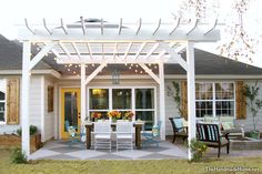 an outdoor dining area is lit up with string lights and patio furniture set on the front lawn