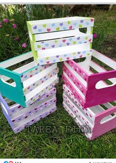 three wooden crates sitting in the grass with polka dot designs on them and one is painted pink