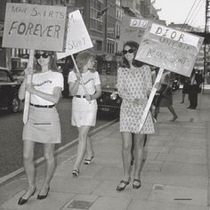 three women walking down the street holding signs