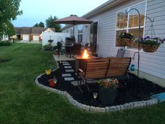 a fire pit sitting in the middle of a yard next to a house with potted plants