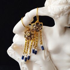 These dainty Roman style earrings follow a common design known as crotalia which is Greek for 'rattle', named for the sound they make when worn. A gold plated filigree flower shape supports three pendants consisting of twisted gold bars, fresh water pearls and genuine dark blue lapis lazuli tube beads with gorgeous gold flecks. Limited edition design. Gold filled ear wires. Length (from top of ear wire to bottom of earring) 5cm (1.96 inches). Please note: All photos are taken under natural light Lingot D'or, Gold Bars, Roman Style, Roman Fashion, Gold Flecks, Earrings Pearl, Gold Bar, Stunning Earrings, Tube Beads