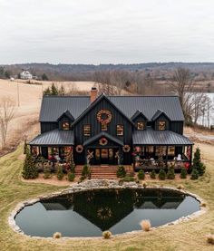 an aerial view of a house with a pond in the foreground and christmas wreaths on the roof