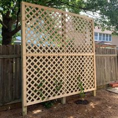 a wooden trellis in the middle of a yard next to a tree and fence