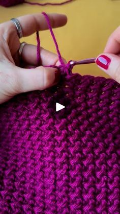 someone is crocheting the stitchs on a purple knitted object with scissors