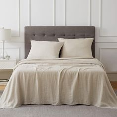 a bed with two pillows on top of it in a room next to a lamp