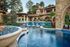 an outdoor swimming pool in front of a large house with columns and arches on the roof