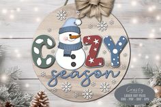 a snowman ornament with the word cozy season on it