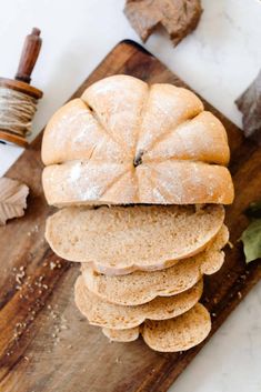 a pile of bread sitting on top of a wooden cutting board next to a sprig of leaves