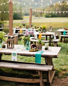 a picnic table with flowers and candles on it in the middle of an open field