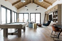 a pool table in the middle of a large room with lots of windows and furniture