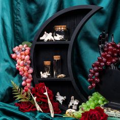 there is a shelf with some wine bottles and grapes next to other items on the table