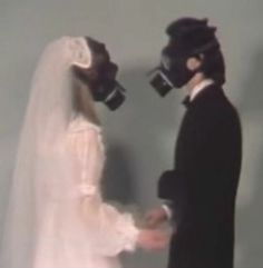 a bride and groom wearing masks standing next to each other