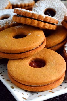 some cookies and pastries are on a white platter with powdered sugar toppings