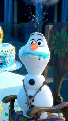 a frozen princess birthday cake with frosting on it and a snowman sitting at the table