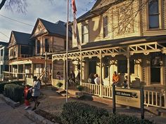 people are walking down the sidewalk in front of old wooden houses with flags on them