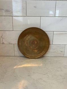 a gold plate sitting on top of a white tiled counter next to a tile wall