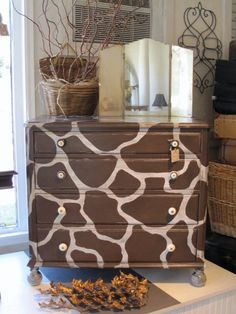 a giraffe print dresser is shown in front of a basket and vase with flowers