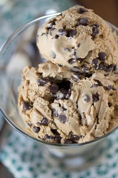 two scoops of ice cream with chocolate chips in a glass bowl on a table