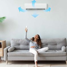 a woman sitting on top of a couch with an air conditioner above her head