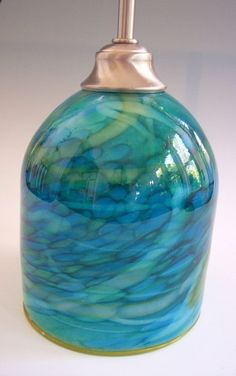 a blue and green vase sitting on top of a white table next to a lamp