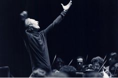 an old photo of a conductor with his arms in the air and hands raised up