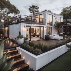 a modern house is lit up at night with lights on the porch and stairs leading to the upper level