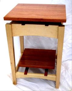 a small wooden table sitting on top of a white sheeted floor with a shelf underneath it