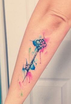 a watercolor tattoo on the arm of a woman with a key and paint splatters