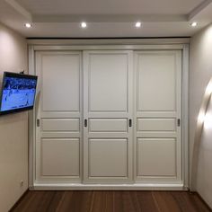 a flat screen tv mounted to the side of a white wall in an empty room