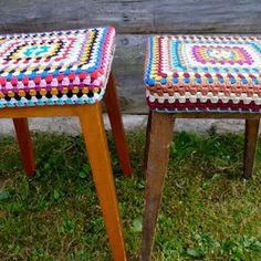 two wooden stools with colorful crocheted seat covers on them sitting in the grass