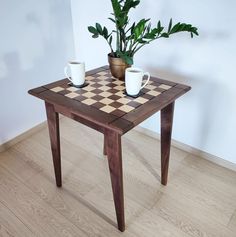 two cups are sitting on a table with a checkerboard pattern in front of it