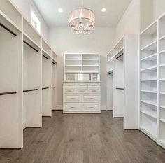 an empty walk in closet with white shelving and wood flooring on the walls