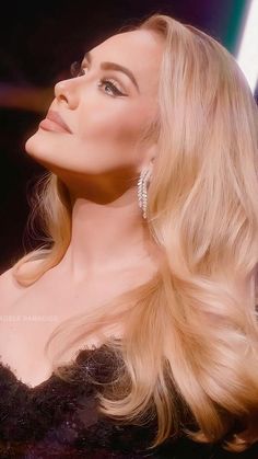 a woman with long blonde hair and diamond earrings on her head looking off into the distance