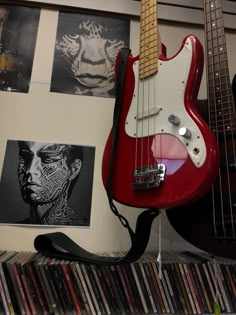 a red guitar sitting on top of a shelf next to a record player's head