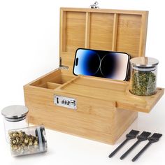 an open wooden box with tea and cell phone in it next to utensils