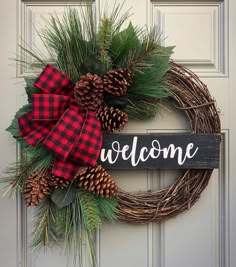 a welcome sign is hanging on the front door with pine cones and evergreens around it