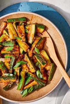 a wooden bowl filled with cooked zucchini on top of a blue and white plate