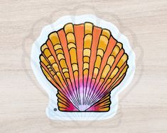 an orange and pink shell sticker sitting on top of a wooden surface