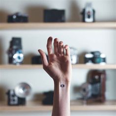 a person's hand with a small tattoo on it, in front of shelves