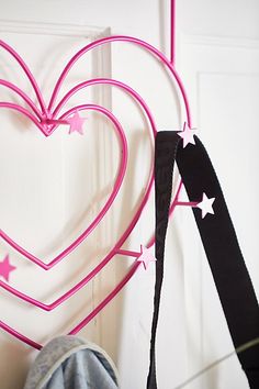 a heart shaped decoration hanging on the wall next to a pair of jeans and shoes