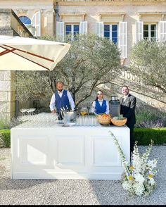 three people standing behind a table with food on it