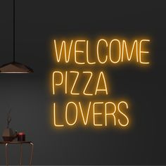 a neon sign that says welcome pizza lovers on the wall next to a table and chair