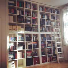 a bookshelf filled with lots of books next to a window