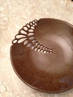 a brown bowl sitting on top of a counter next to a black object with holes in it