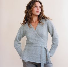 a woman standing with her hands on her hips wearing a gray sweater and grey pants